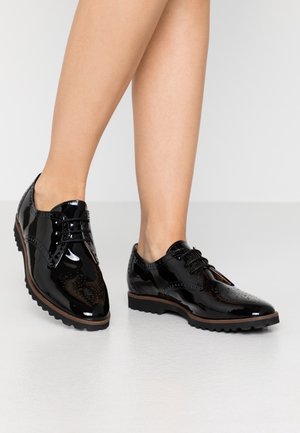 Sorte oxfords i laklæder med brogue-detaljer, snørestil og gummisål. Har en glat tekstur og rundet tådesign.
