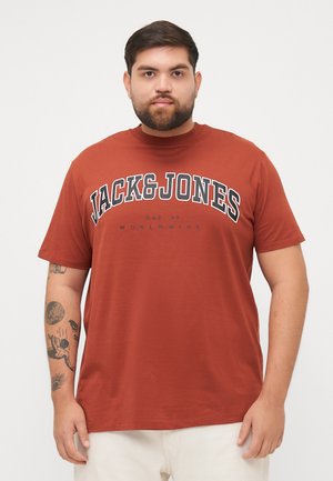 Rustfarget kortermet t-skjorte laget av mykt stoff. Har fet svart tekst "JACK&JONES" med "EST. 90 WORLDWIDE" under.