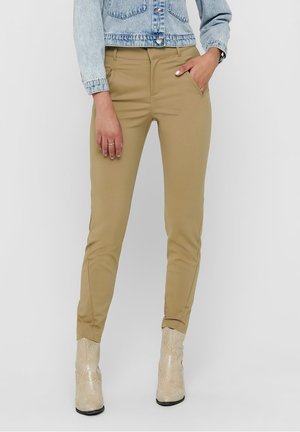 Tanskleurige slim fit broek met zijzakken, met een gladde textuur en een taps toelopend ontwerp bij de enkels. Gecombineerd met een lichtblauwe denim jacket.