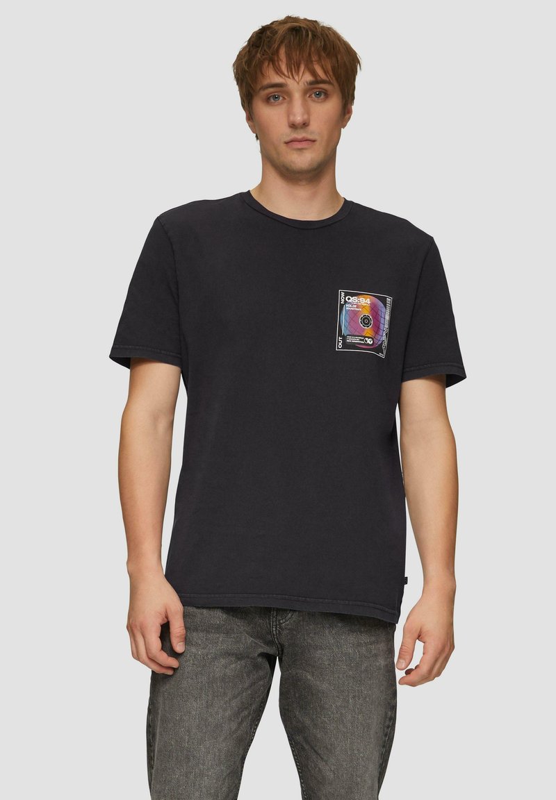 Zwarte katoenen t-shirt met een grafische patchzak met een multicolor ontwerp. Korte mouwen en ronde hals. Eenvoudige, casual pasvorm.