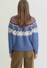 Pull en tricot bleu avec un design Fair Isle présentant des motifs orange, rose et noir, ourlet côtelé et coupe décontractée.
