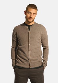 Hnědý vlněný cardigan s kulatým výstřihem, ozdobený knoflíkovým zapínáním a ribovými manžetami. Hladká textura a přiléhavý střih.