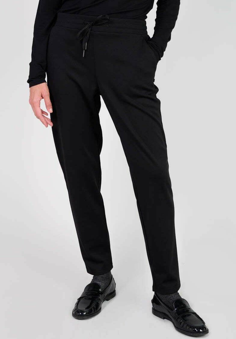 Svarta joggingbyxor i elastisk tyg med dragsko i midjan, smal passform och sidofickor. Släta textur med minimalistisk design.