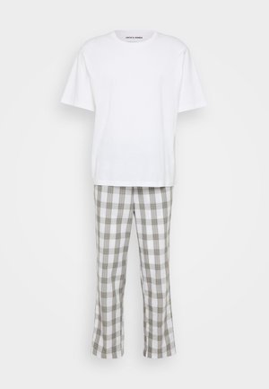 Balta medvilninė marškinė su trumpomis rankovėmis, dėvimi su tamsyniais plaid stiliaus kelnėmis, su balta, pilka ir smėlio spalvomis, pasižyminčios laisvu kirpimu ir šiek tiek platėjančiomis klešnėmis.