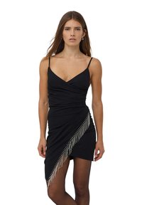 Czarna, bezrękawnikowa sukienka z dekoltem w kształcie litery V, diagonalnym drapowaniem i srebrnymi frędzlami po jednej stronie. Gładki materiał, dopasowany fason, do kolan.