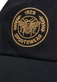 Schwarze Kappe mit einem goldgestickten Emblem, das eine Biene und Lorbeerakzente zeigt, beschriftet mit "1923 SPORTSWEAR" in einem kreisförmigen Design.