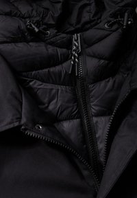 Černá zateplená bunda s hladkou texturou, vybavená předním zipem, nastavitelnými šňůrkami a prošívanou podšívkou.