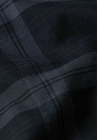 Tessuto a quadri in tonalità scure di blu e nero, caratterizzato da una texture morbida e linee diagonali che creano un delicato motivo a check.
