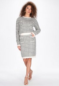 Fekete-fehér kockás pulóver és szoknya szett, frufrus szélekkel, zsebekkel és hosszú ujjakkal, texturált kötött anyagból készült.