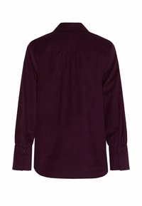 Chemise en velours côtelé violet foncé avec un empiècement au dos, manches longues et poignets à boutons. Dispose d'un col classique et d'une coupe décontractée.