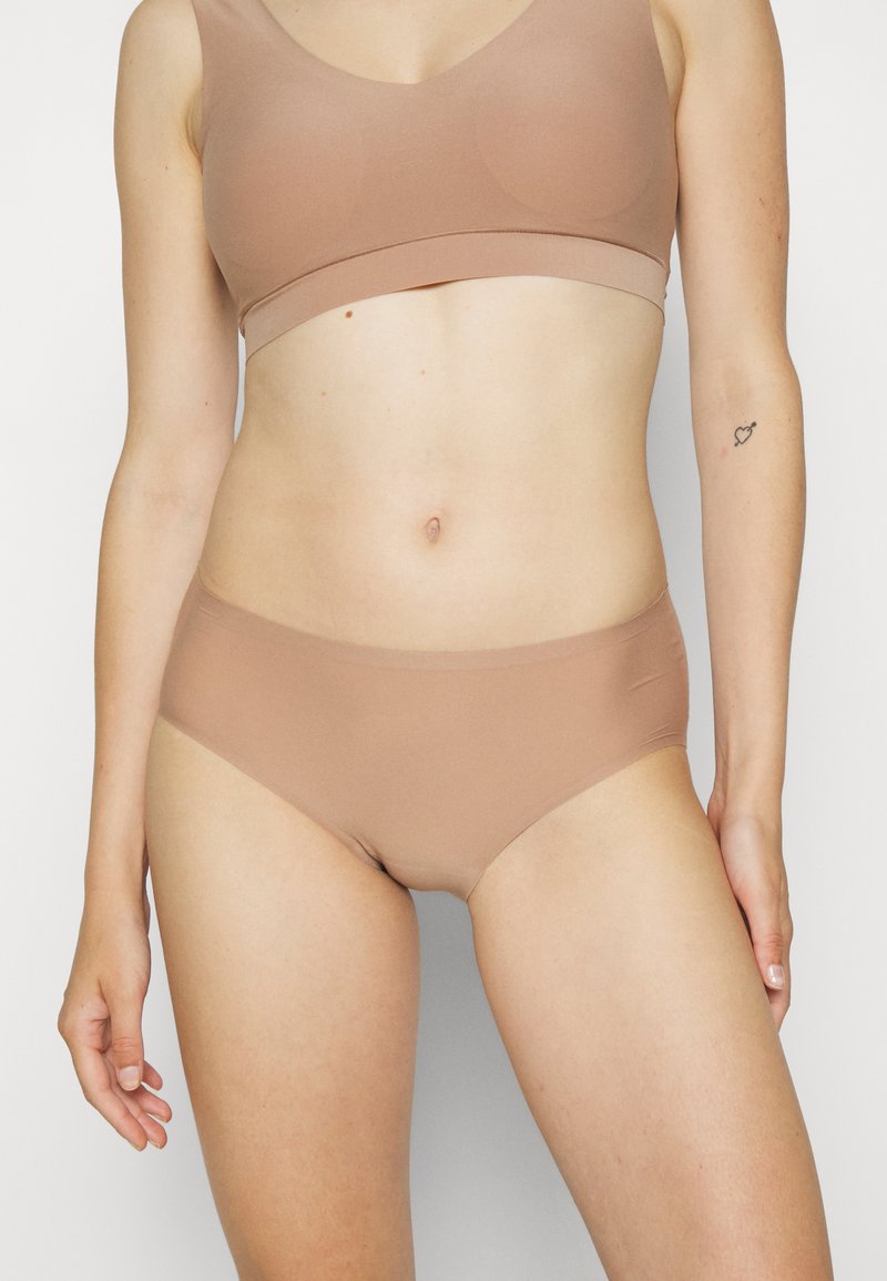 Bežs bezšuvju bralete un atbilstošs hipster apakšbikses komplekts. Izgatavots no mīkstas, elastīgas auduma ar gludu tekstūru un bez redzamām šuvēm.