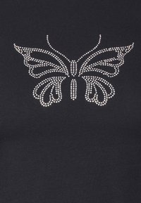 Černý top z látky s motivem motýla, který je vyrobený z malých stříbrných kamínků, zvýrazňující složité vzory křídel a jemné detaily.