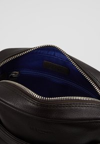 Borsa in pelle marrone con apertura zip, dotata di una brillante fodera in raso blu e una tasca interna con zip per un'organizzazione ottimale.