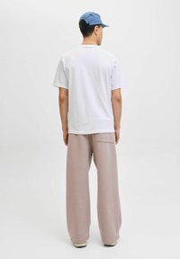 Tricou alb, croi lejer, asortat cu pantaloni de trening roz deschis, cu picioare largi, având un buzunar pe spate. O șapcă albastră completează ținuta.