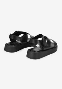 Sandalias de plataforma negras hechas de material sintético suave. Presentan correas entrelazadas y correas ajustables en el tobillo con un diseño elegante.
