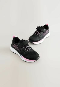 Chaussures de sport noires avec des accents roses, dotées d'un dessus texturé, de lacets élastiques et d'une sangle Velcro. La semelle intermédiaire présente un design blanc et rose.