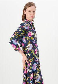 Floral dress with a navy background, featuring pink and blue flowers. Long sleeves and a button-down front. Soft fabric with a flowy silhouette.