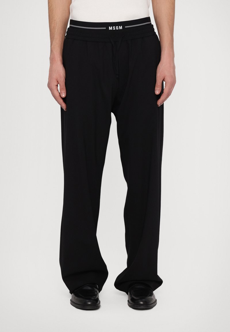 Black, wide-leg pants made of smooth fabric, featuring an elastic waistband with a white "MSGM" logo and drawstring for adjustable fit.