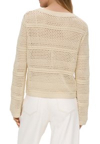 Pull en maille beige avec un design ajouré, manches longues et ourlet côtelé. Le dos présente des motifs horizontaux et verticaux.