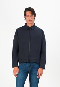 Marineblå jakke med krage, frontlynlås og lange ermer; har et ensfarget design og en kortet passform ved midjen.