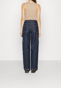 Mörkblå denim cargobyxor med lös passform, med sidofickor och hög midja. Tyget har en slät textur och minimala sömnadsdetaljer.