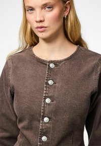 Top in denim marrone con scollatura rotonda, caratterizzato da bottoni argentati al centro e un tessuto morbido e testurizzato. Design semplice e strutturato.
