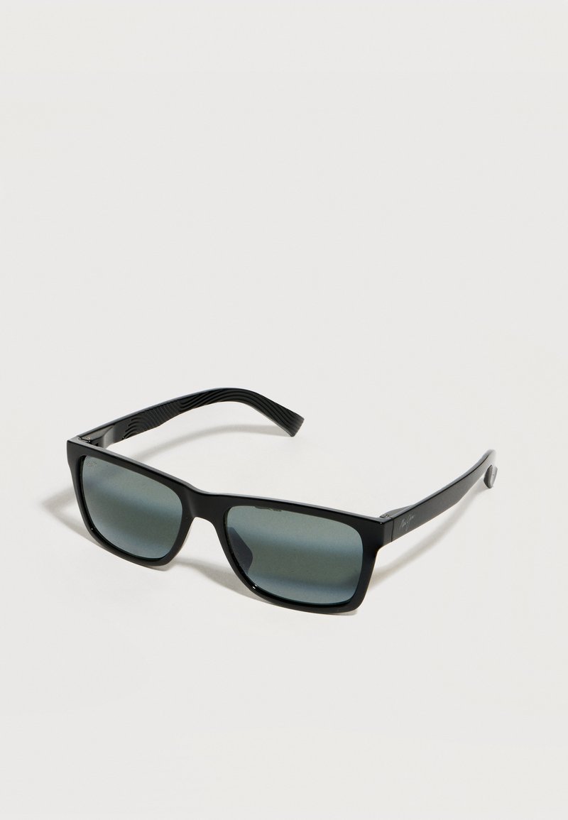 Μαύρα ορθογώνια γυαλιά ηλίου με σκούρους φακούς και ελαφρώς καμπυλωτούς, υφασμένους βραχίονες πάνω σε ανοιχτό φόντο.