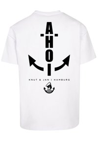 Witte katoenen T-shirt met een zwarte grafische print met de tekst "AHOI" en pijlen, samen met "KNUT & JAN | HAMBURG" en een zeilerlogo.