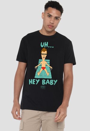 Schwarzes Baumwoll-T-Shirt mit einem Grafikdruck eines Cartoon-Charakters auf einer Liege, der rote Badehosen trägt, begleitet von dem Text "UH... HEY BABY."
