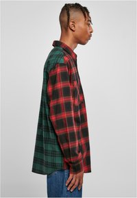 Geruite shirt met rood en zwart aan de ene kant, groen aan de andere kant. Lange mouwen, kraag en pocketdetail. Gemaakt van geweven stof.