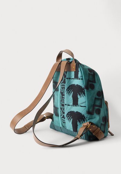 Sac à dos sarcelle avec imprimé noir de palmier, bretelles en cuir marron réglables et ferrures dorées sur fond clair uni.