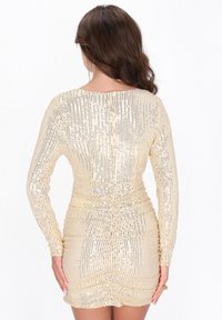 Langärmliges, tailliertes Mini-Kleid in Gold mit strukturierten Pailletten, Raffung an der Taille und rundem Ausschnitt. Glatte, schimmernde Oberfläche.