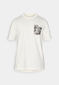 T-shirt en coton blanc à manches courtes, avec un design de poche grise comportant un logo circulaire. Col rond et coupe décontractée.