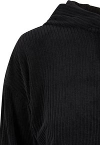Pull en tissu côtelé noir avec un col haut doux et plié et des manches longues, vu de dos en haut.