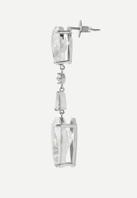 Orecchini pendenti in tonalità argento con ampie pietre di cristallo trasparenti sfaccettate in montature metalliche verticali, collegate da pietre più piccole e trasparenti.