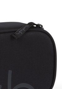Custodia di fabric nera con forma rettangolare, dotata di chiusura a zip e superficie testurizzata. Include un'etichetta con la parola "Sofach."