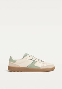 Sneakers with a light beige leather upper, mint green accents, beige rubber sole, rounded shape, and contrasting textured panels.