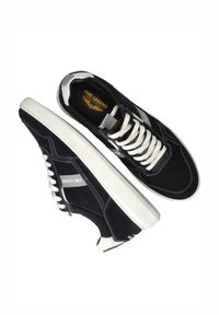 Black suede sneakers with white laces and sole. Features gray accents, a textured rubber sole, and branding on the side and insole.