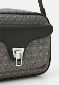 Borsa a tracolla in materiale grigio testurizzato con dettagli in pelle nera e hardware argentato. Presenta un motivo geometrico e una chiusura sicura.