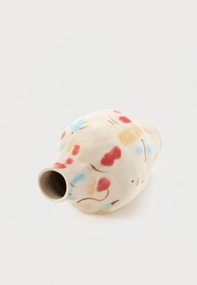 Στρογγυλό κεραμικό βάζο με ακανόνιστο σχήμα, διακοσμημένο με κόκκινα, μπλε και μπεζ αφηρημένα λουλουδένια σχέδια σε λευκό φόντο.