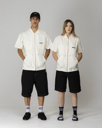 Cream short-sleeve jackets with two front pockets; paired with black shorts. Black socks and shoes complement the outfits.