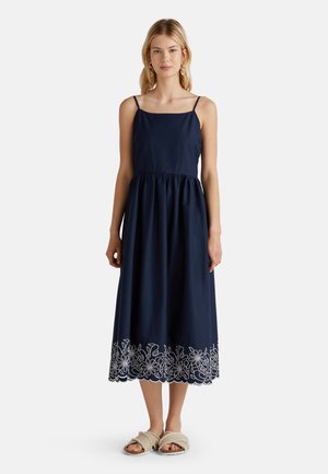 Marineblaues, ärmelloses Kleid mit enganliegendem Oberteil und geraffter Taille. Verfügt über weiße Blumenstickerei am Saum.