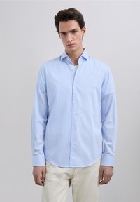 Hellblau gestreiftes Hemd mit Knöpfen, klassischem Kragen, langen Ärmeln und abgerundetem Saum, hergestellt aus glattem Stoff.