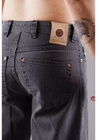 Gray denim jeans with a textured finish, featuring a leather label, copper rivets, and visible back pockets.