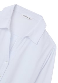 Camicia bianca a maniche lunghe realizzata in tessuto leggero, con colletto classico, apertura con bottoni e vestibilità rilassata. Etichetta indica la taglia small.