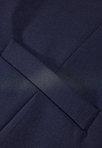 Navystoff mit glatter Textur und subtiler Eleganz, an einer Seite mit überlappendem Detail und einem sauberen, maßgeschneiderten Erscheinungsbild.