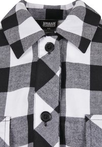Camicia a righe bianco e nero con colletto e bottoni neri, con etichetta del brand Urban Classics in taglia XS.