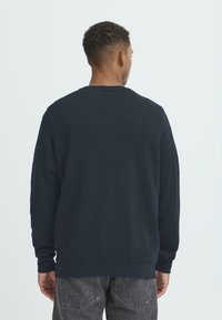 Marineblaues Sweatshirt mit Rundhalsausschnitt, langen Ärmeln und gerippten Bündchen. Hergestellt aus weichem Stoff, zeichnet es sich durch eine lockere Passform und minimale Details aus.