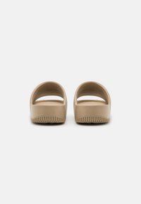 Beige slip-on sandals with an open back and rounded design. Smooth plastic material with a textured sole for grip.