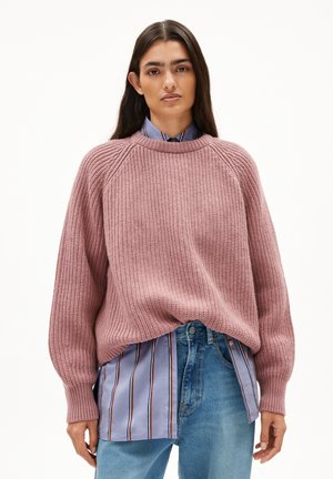 Knit sweater in dusty pink with ribbed texture and dropped shoulders, paired with a light blue striped shirt and denim jeans.